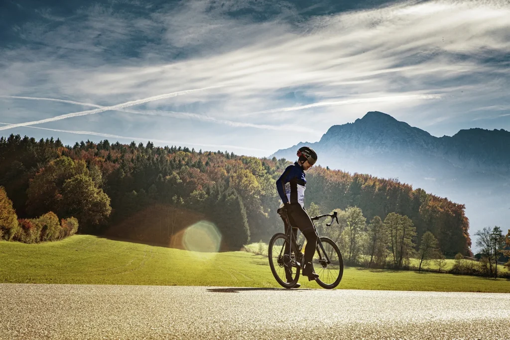 Rennradfahrer auf einer Landstraße vor Bergpanorama im Salzburger Land